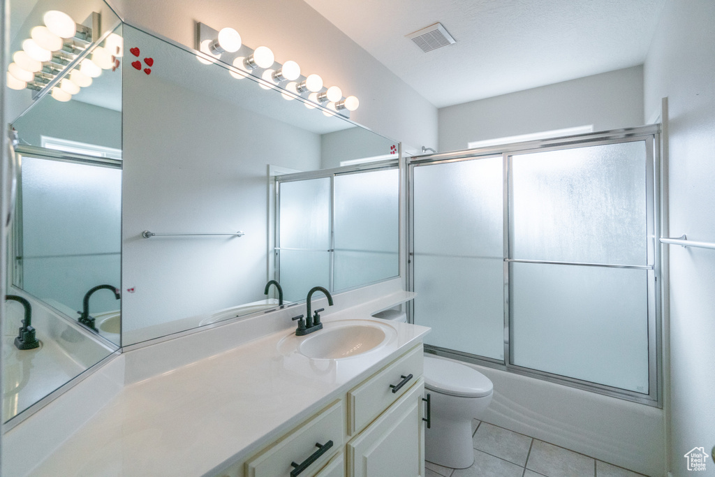 Full bathroom featuring combined bath / shower with glass door, tile flooring, oversized vanity, and toilet