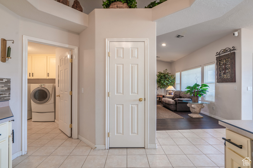 Laundry room with cabinets, light tile floors, and washer / clothes dryer