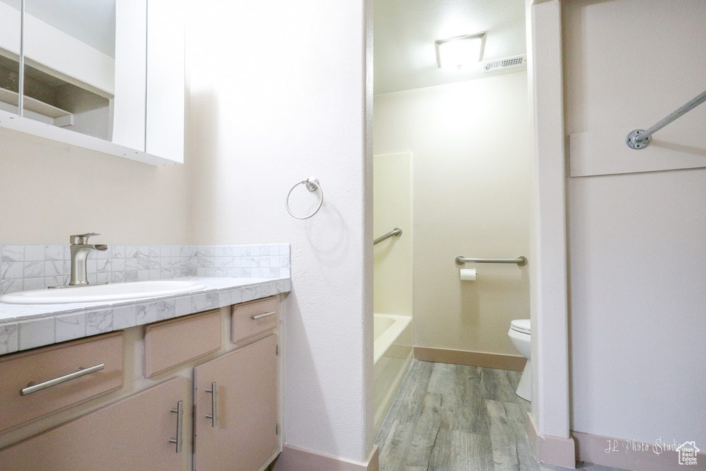 Full bathroom featuring vanity, toilet, bathtub / shower combination, and wood-type flooring
