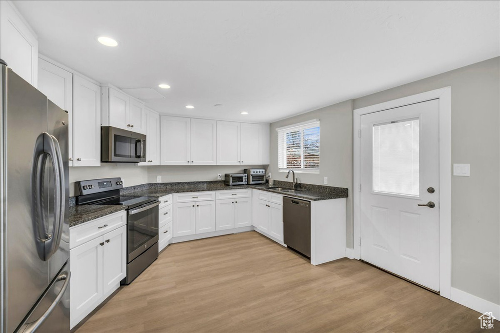 Kitchen with white cabinets, light hardwood / wood-style floors, sink, and stainless steel appliances