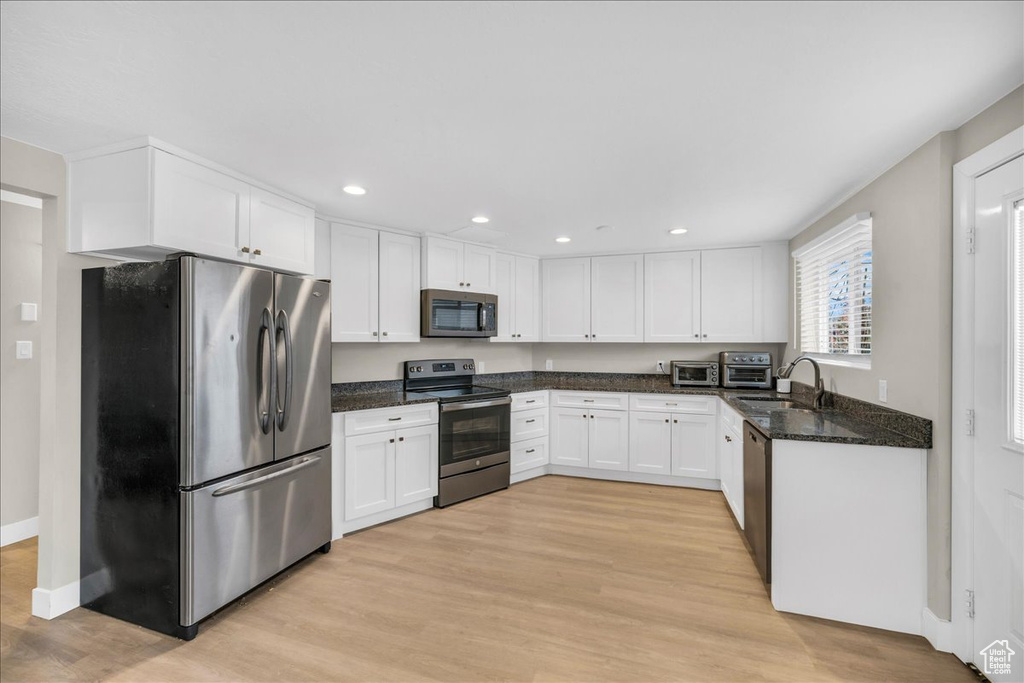 Kitchen featuring white cabinetry, sink, appliances with stainless steel finishes, and light wood-type flooring