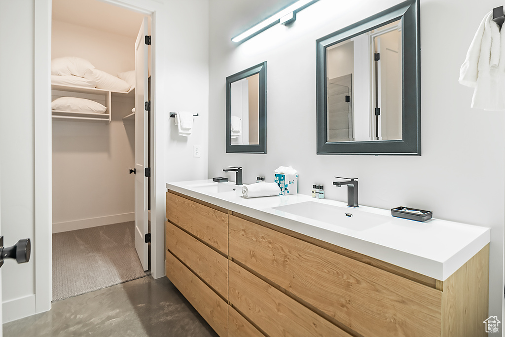 Bathroom with concrete flooring, dual sinks, and vanity with extensive cabinet space