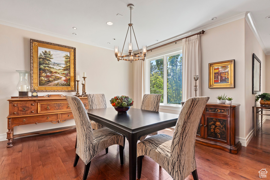 Dining area featuring crown molding, an inviting chandelier, and dark hardwood / wood-style floors
