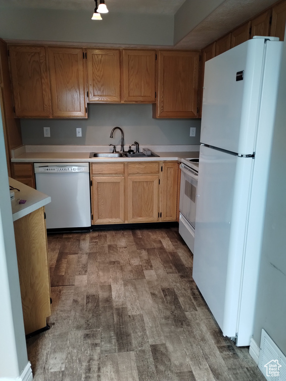 Kitchen featuring white appliances, sink, and dark wood-type flooring