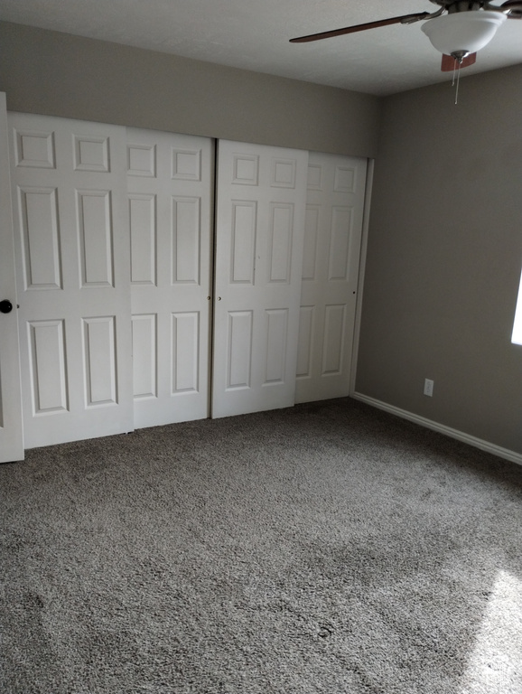 Unfurnished bedroom featuring ceiling fan and carpet