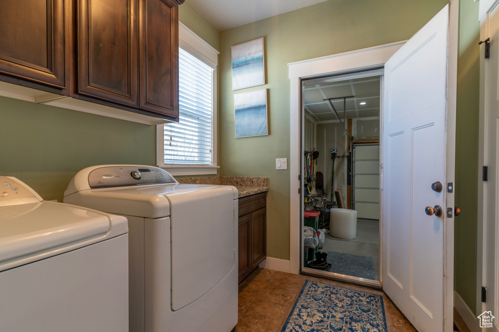 Laundry area with light tile flooring, washer and dryer, and cabinets