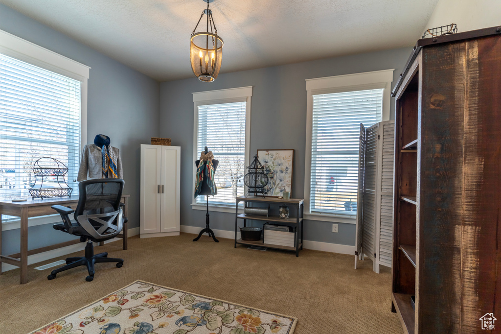 Office with an inviting chandelier, light colored carpet, and a healthy amount of sunlight