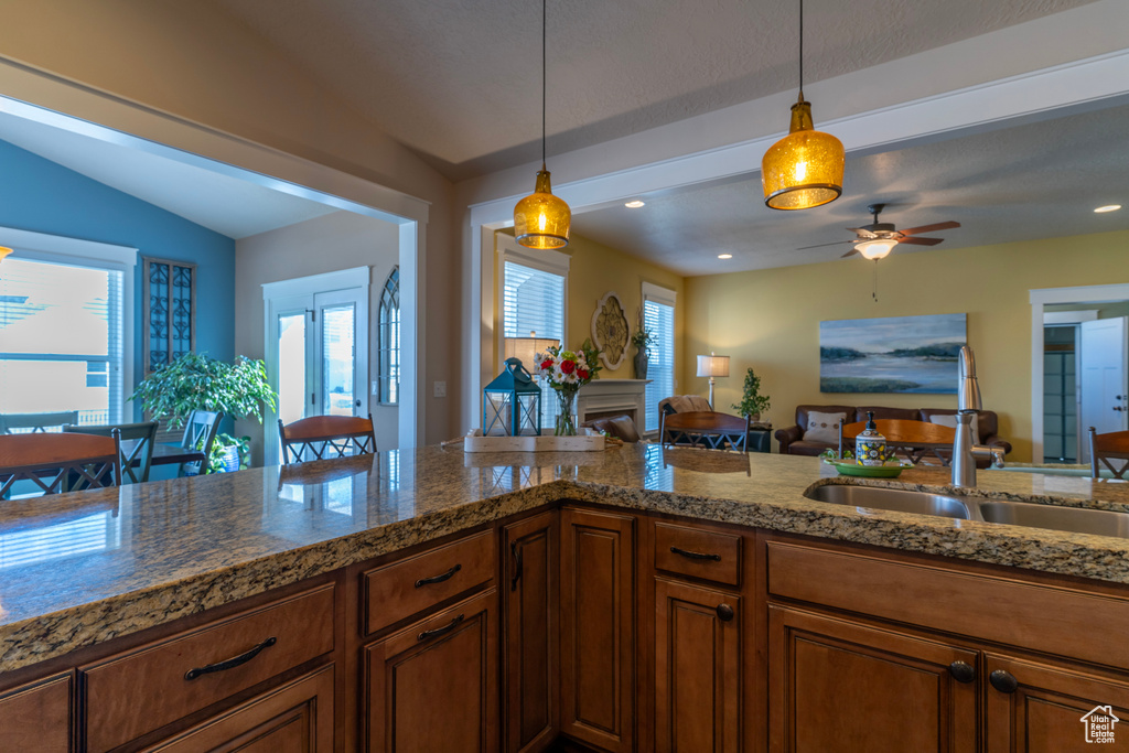 Kitchen featuring vaulted ceiling, decorative light fixtures, ceiling fan, and sink