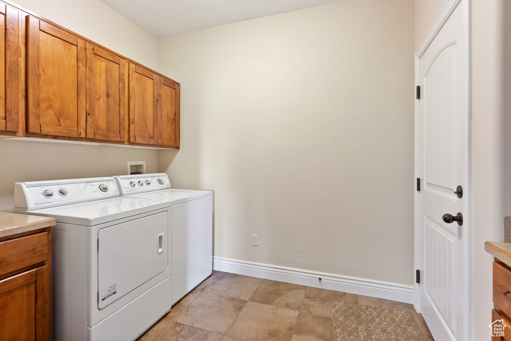 Washroom with washing machine and clothes dryer, light tile floors, hookup for a washing machine, and cabinets