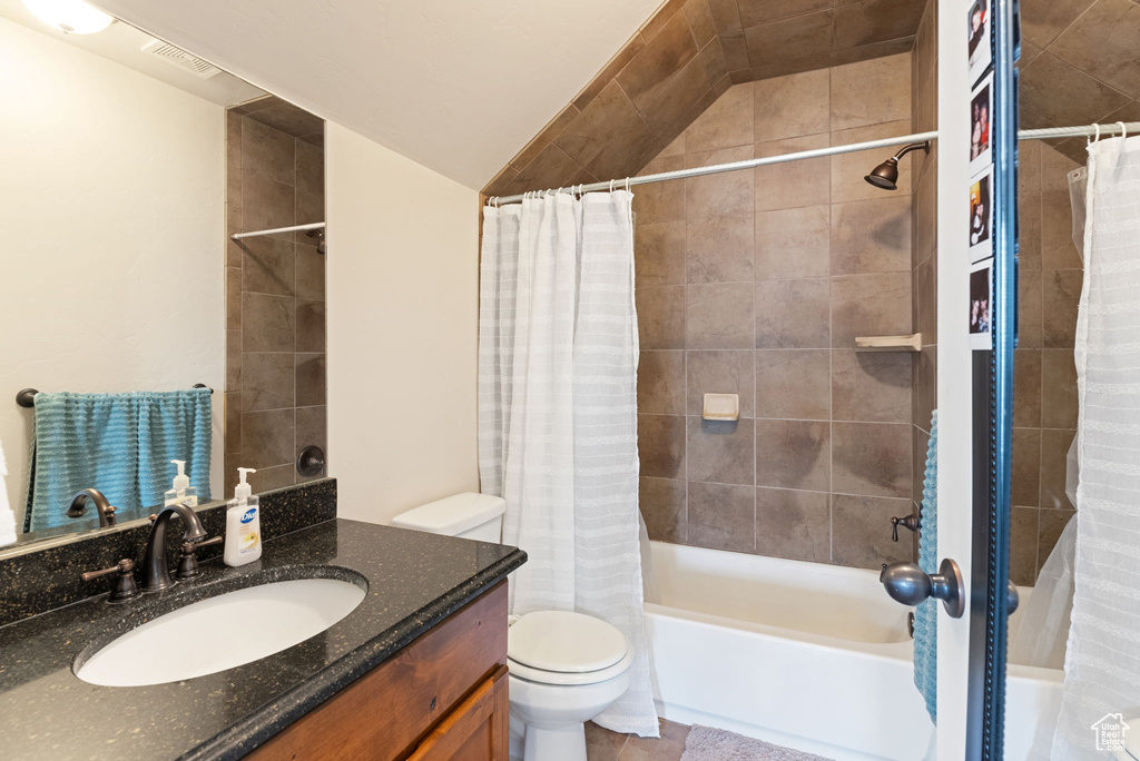 Full bathroom featuring shower / tub combo with curtain, tile floors, oversized vanity, and toilet
