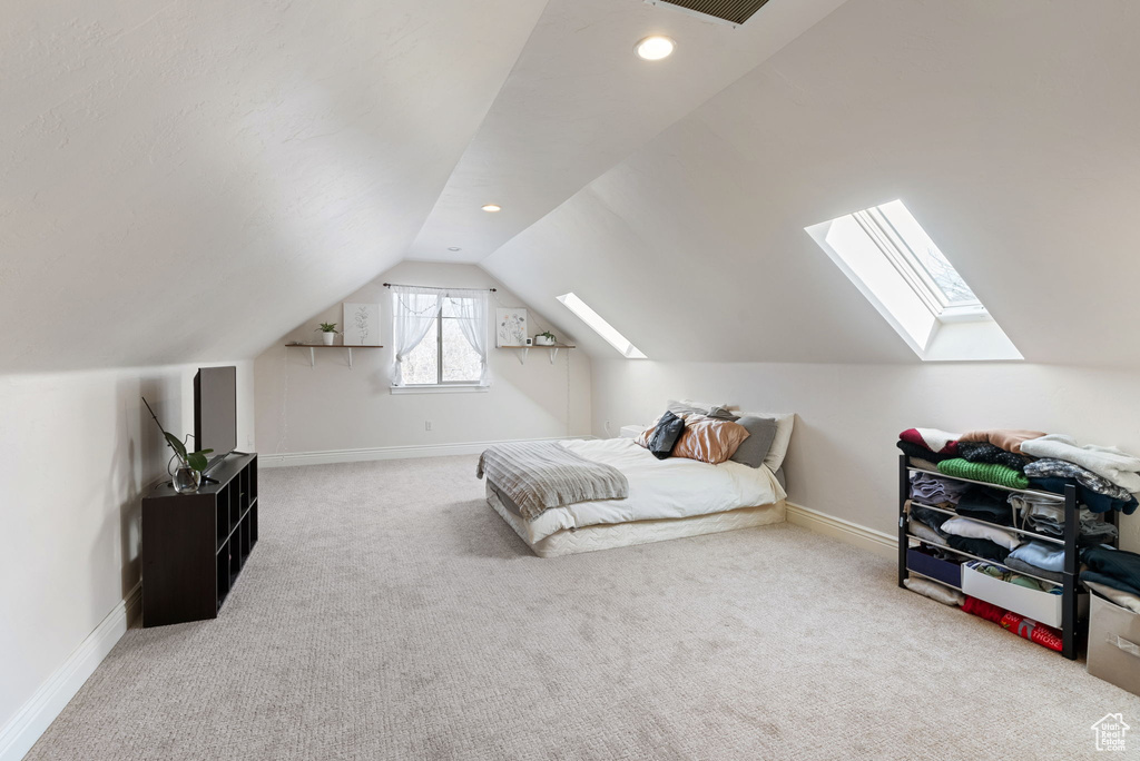 Bedroom featuring vaulted ceiling with skylight and light carpet