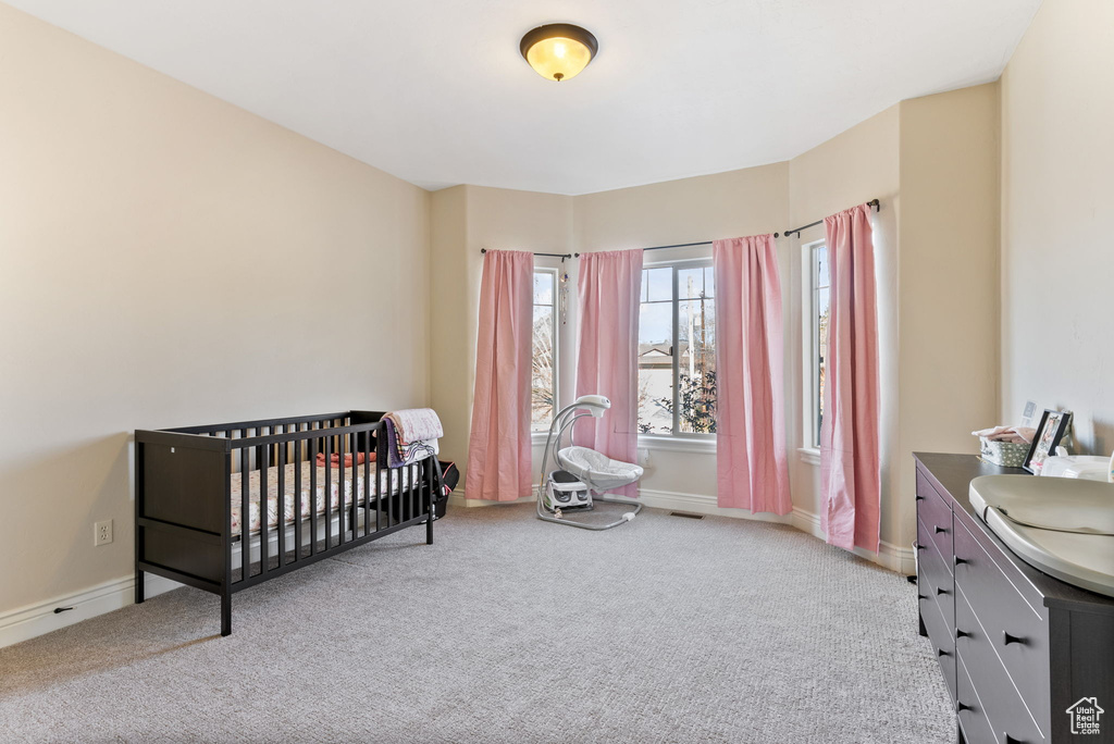 Bedroom with a nursery area and light carpet