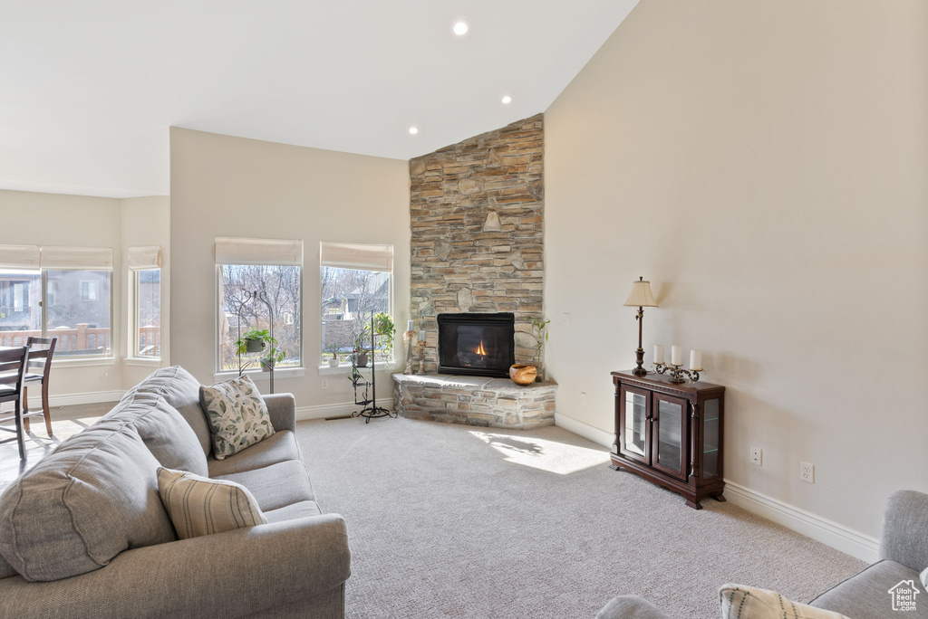 Carpeted living room with high vaulted ceiling and a stone fireplace