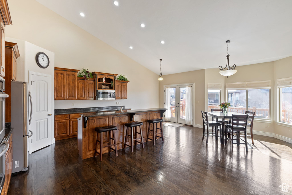 Kitchen with pendant lighting, dark hardwood / wood-style flooring, stainless steel appliances, french doors, and a breakfast bar area