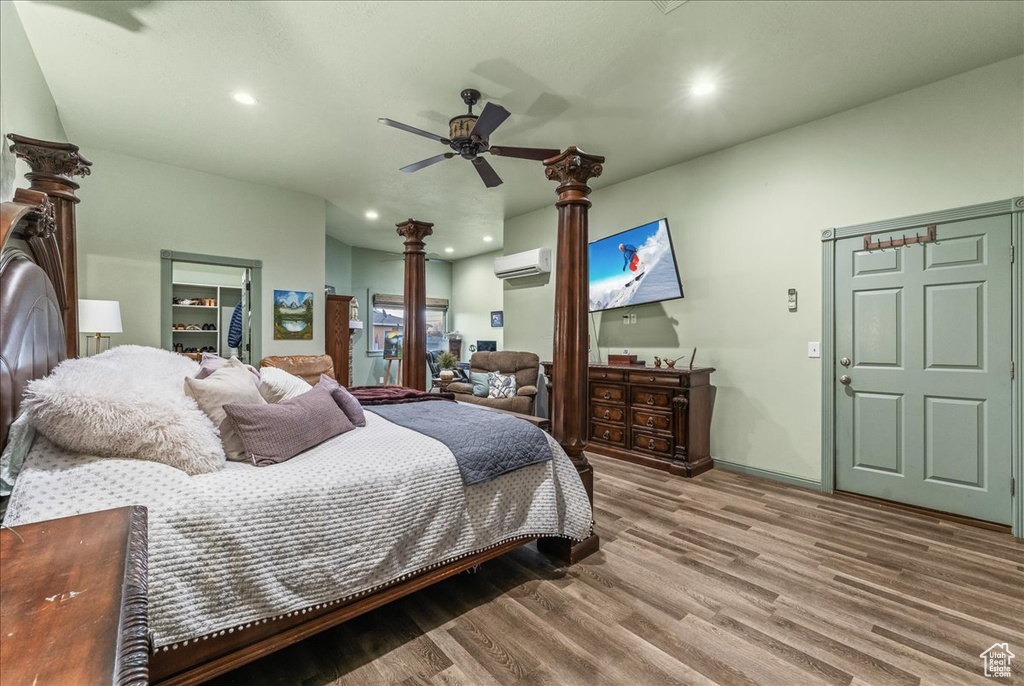 Bedroom featuring hardwood / wood-style floors, a wall unit AC, and ceiling fan