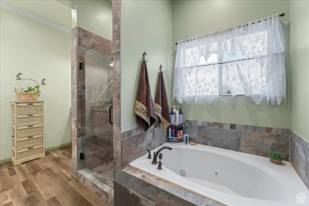 Bathroom with separate shower and tub, ornamental molding, and hardwood / wood-style flooring