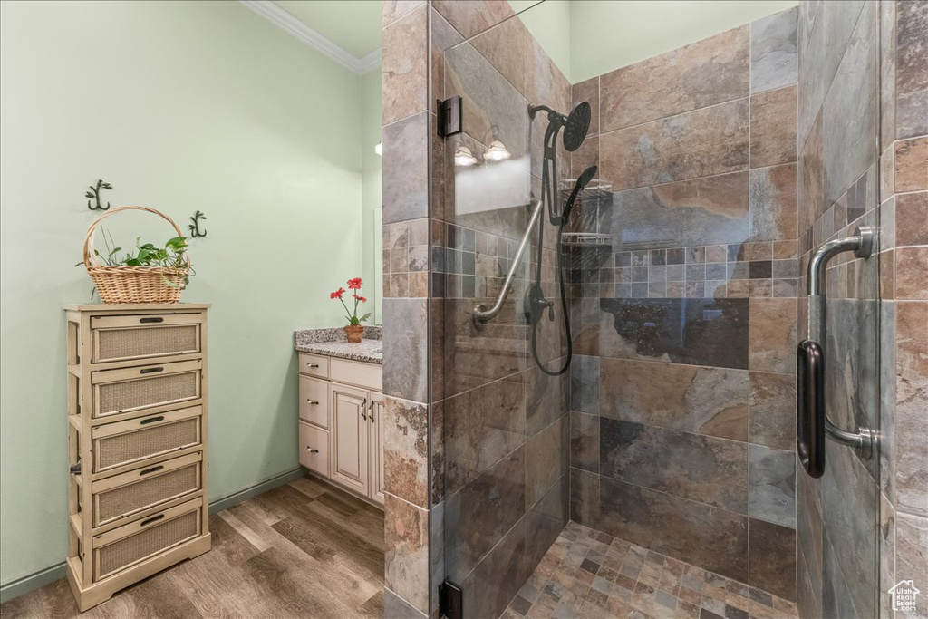 Bathroom featuring vanity, walk in shower, crown molding, and wood-type flooring