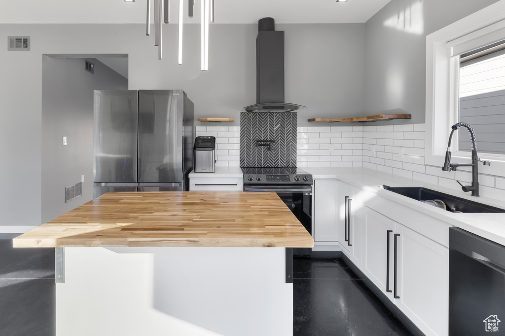 Kitchen featuring backsplash, black appliances, white cabinets, sink, and exhaust hood