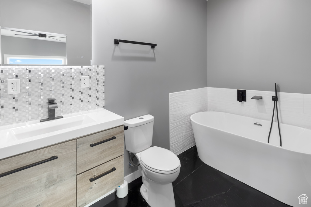Bathroom featuring vanity, tasteful backsplash, toilet, a bath, and ceiling fan