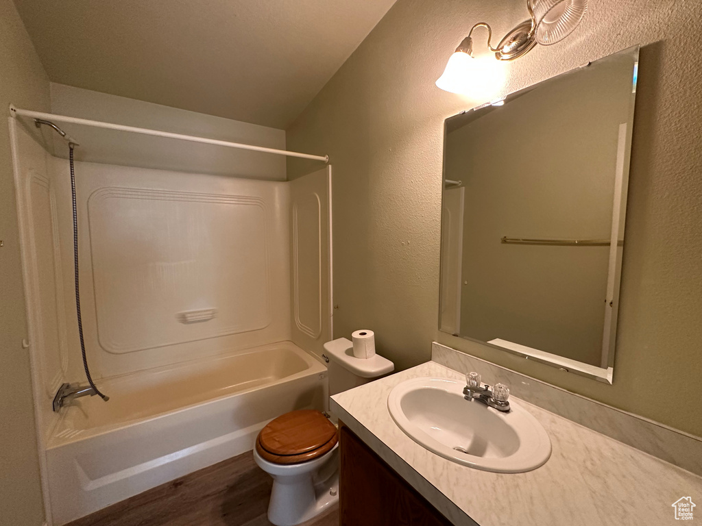 Full bathroom with wood-type flooring, vanity, shower / tub combination, and toilet