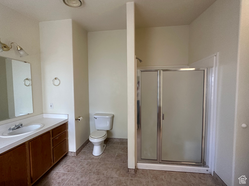 Bathroom with a shower with shower door, tile floors, vanity, and toilet