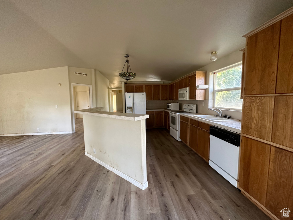 Kitchen featuring hardwood / wood-style floors, white appliances, lofted ceiling, sink, and decorative light fixtures