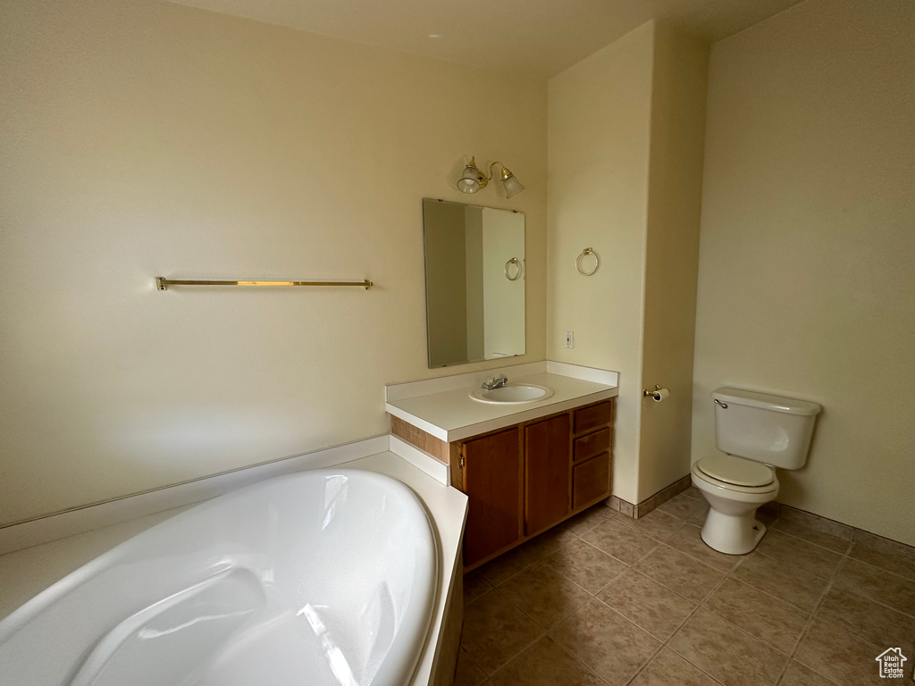Bathroom featuring toilet, a bathtub, large vanity, and tile flooring