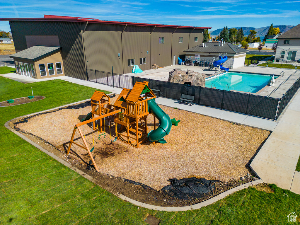 View of jungle gym with a fenced in pool, a yard, and a patio area