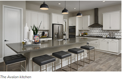 Kitchen featuring hanging light fixtures, a breakfast bar, stainless steel appliances, and wall chimney range hood