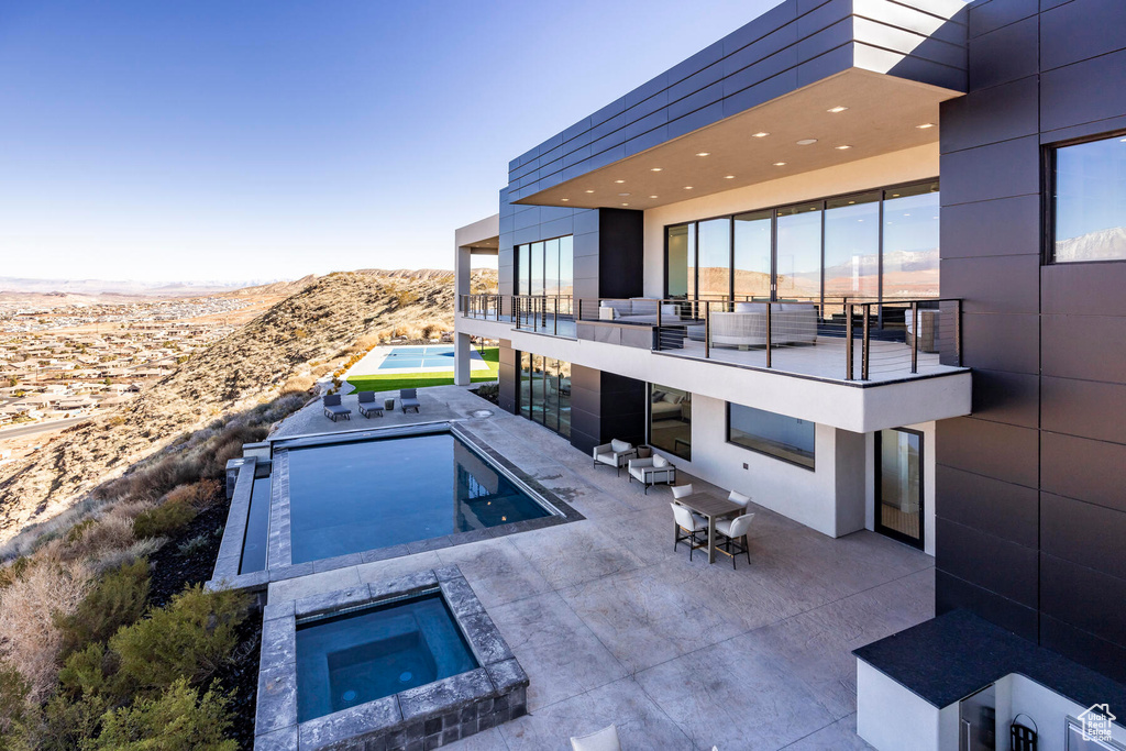 View of swimming pool with a mountain view, a patio area, and an in ground hot tub