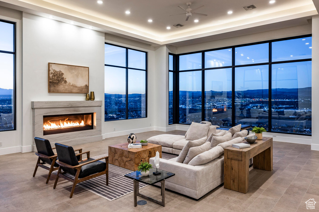 Living room featuring a mountain view, a towering ceiling, light tile floors, a premium fireplace, and ceiling fan