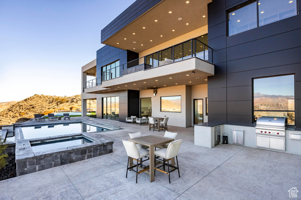 View of patio / terrace with a balcony, a pool with hot tub, area for grilling, an outdoor kitchen, and a mountain view