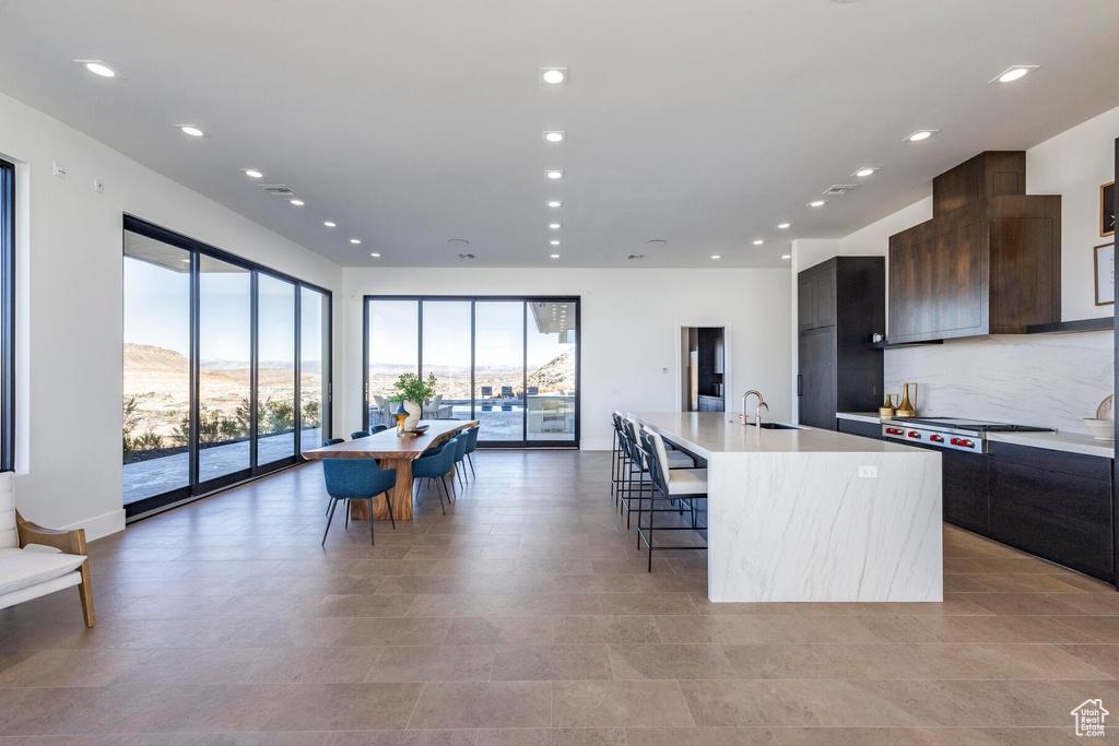 Kitchen featuring stainless steel gas stovetop, light tile patterned floors, and an island with sink