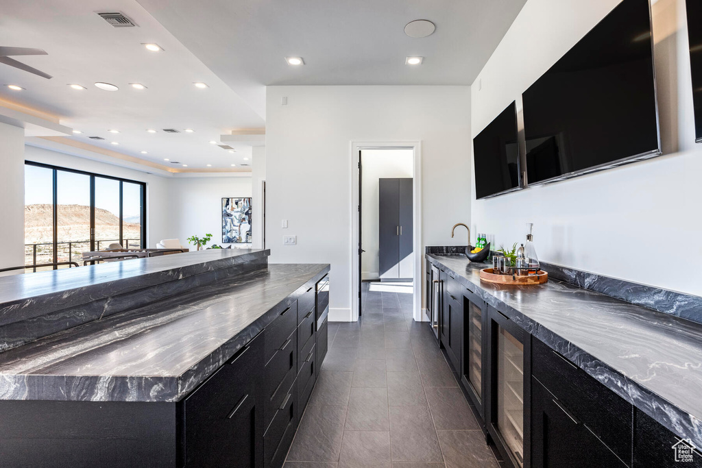 Kitchen with sink, dark tile patterned floors, beverage cooler, and a kitchen island