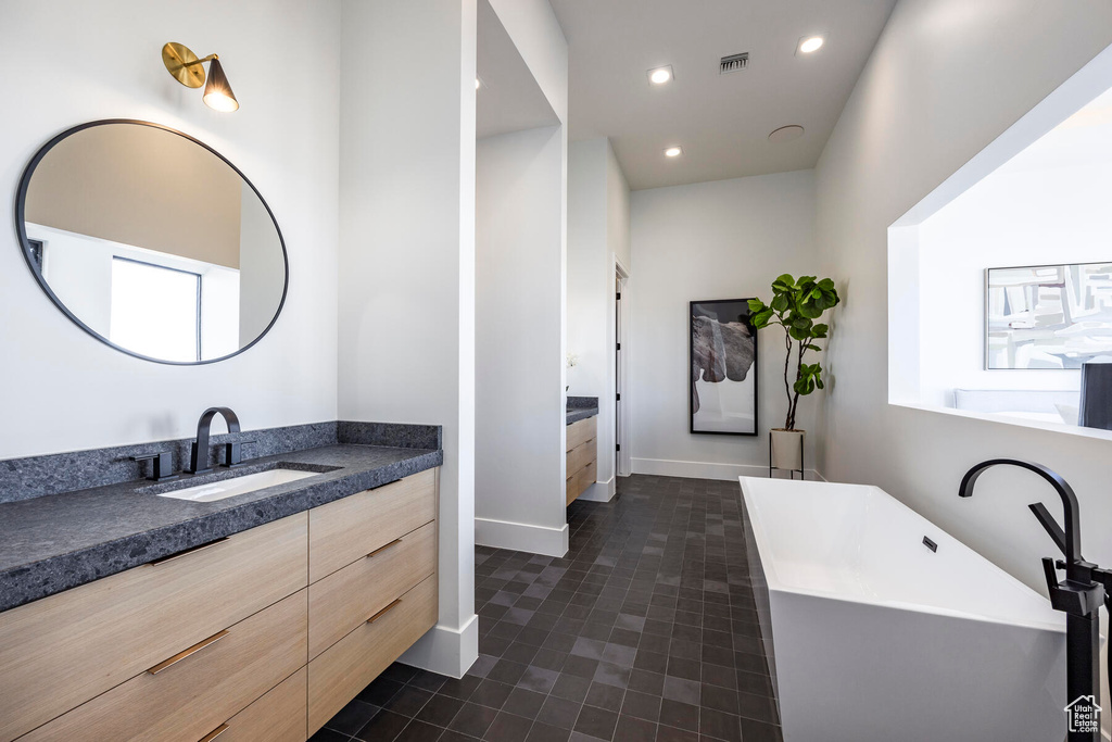 Bathroom featuring tile patterned flooring, a tub, and vanity