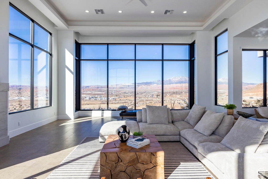 Living room with a mountain view, dark tile patterned flooring, a wealth of natural light, and a raised ceiling