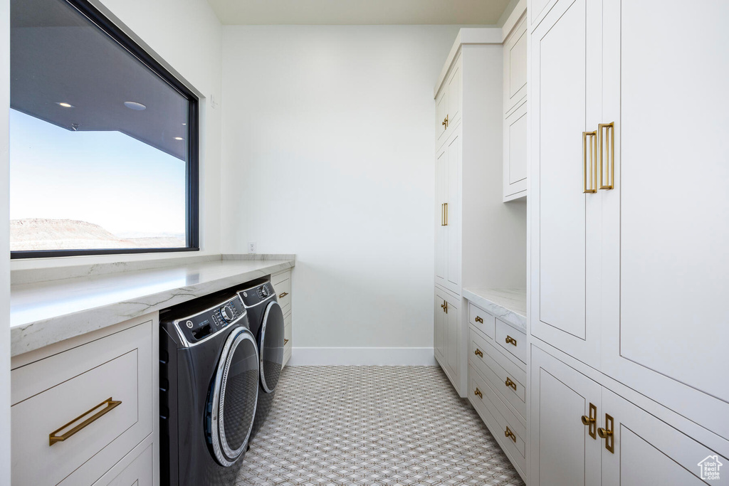 Washroom featuring cabinets, washing machine and dryer, and light colored carpet