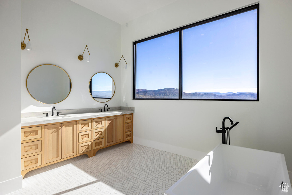 Bathroom featuring dual vanity, tile patterned floors, and a tub