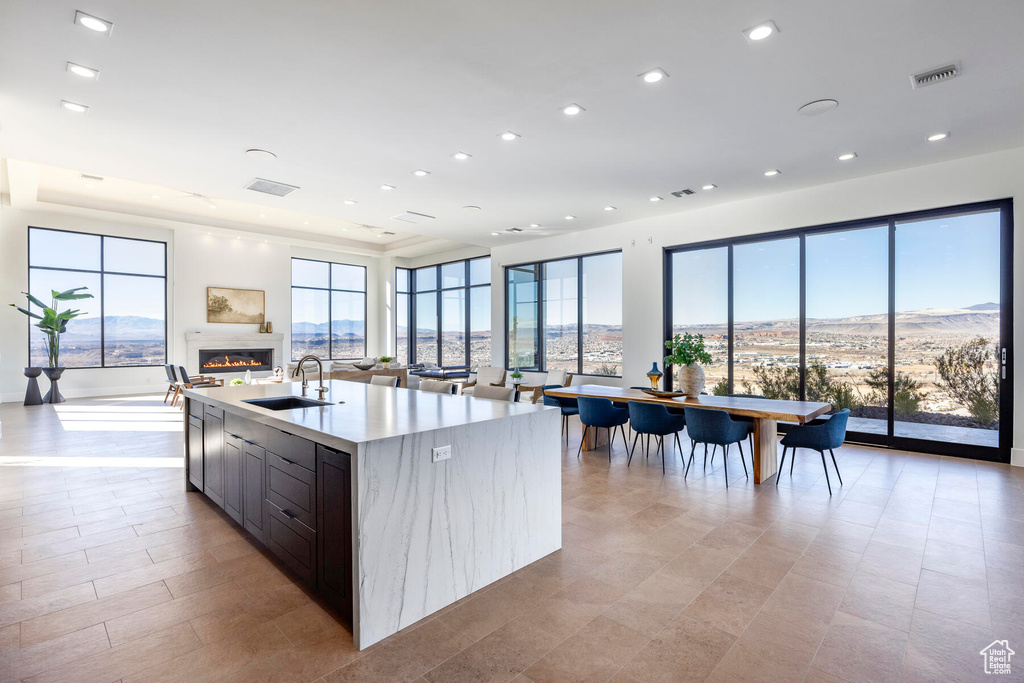 Kitchen featuring sink, light tile patterned floors, and a center island with sink