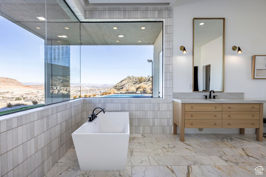 Bathroom featuring a tub, vanity, a mountain view, tile walls, and tile floors