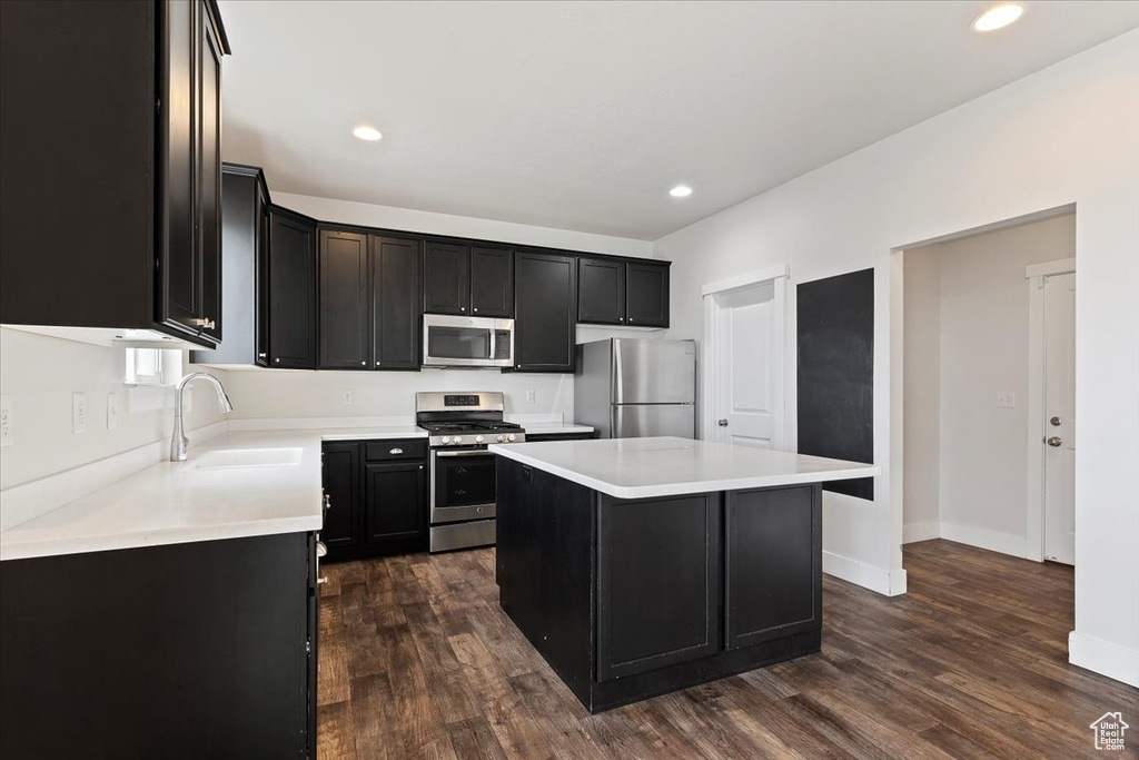 Kitchen featuring dark hardwood / wood-style floors, appliances with stainless steel finishes, a center island, and sink