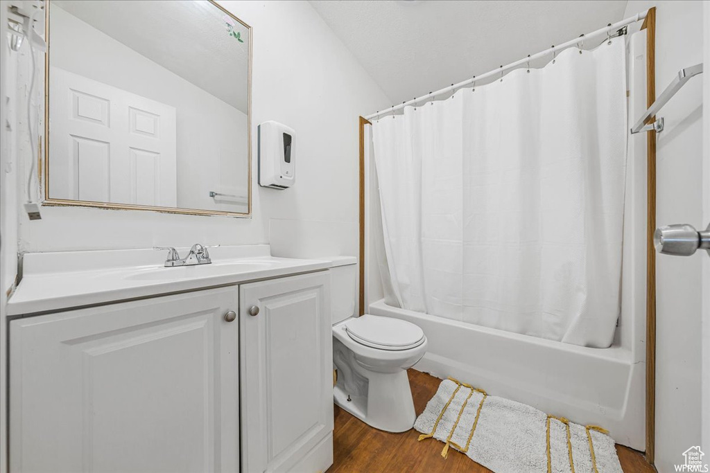 Full bathroom with shower / bath combo with shower curtain, hardwood / wood-style flooring, vanity, toilet, and lofted ceiling