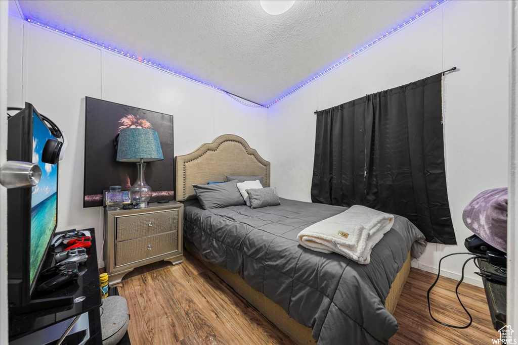 Bedroom with hardwood / wood-style floors and a textured ceiling