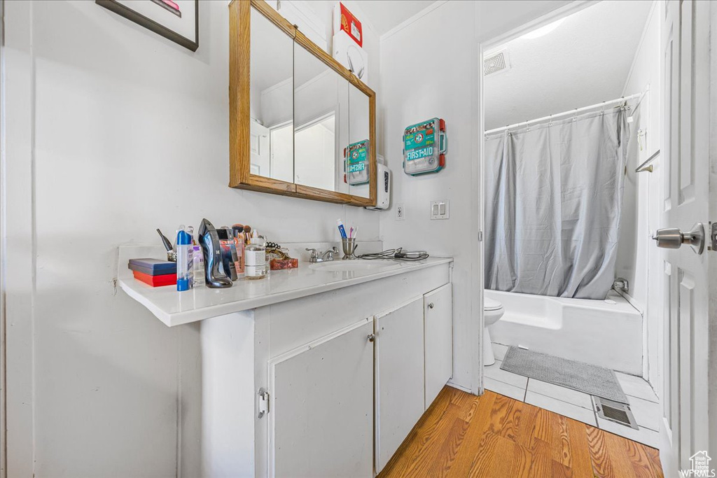 Full bathroom with shower / bath combo with shower curtain, wood-type flooring, vanity, and toilet
