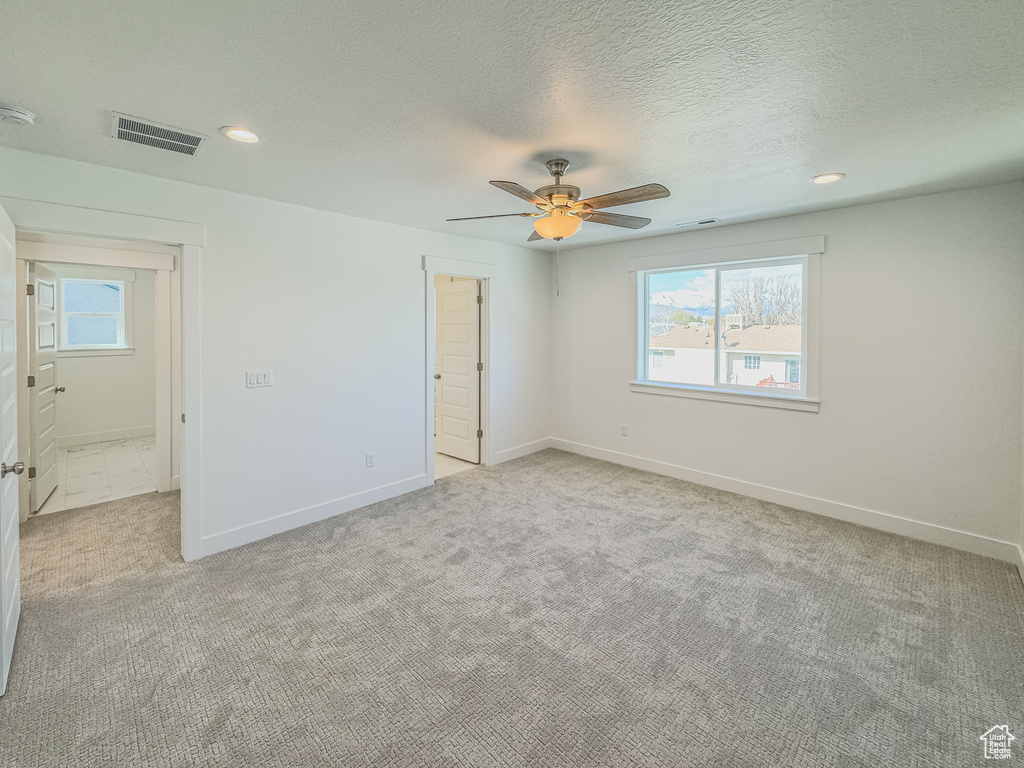 Unfurnished bedroom featuring ceiling fan, light colored carpet, and a textured ceiling