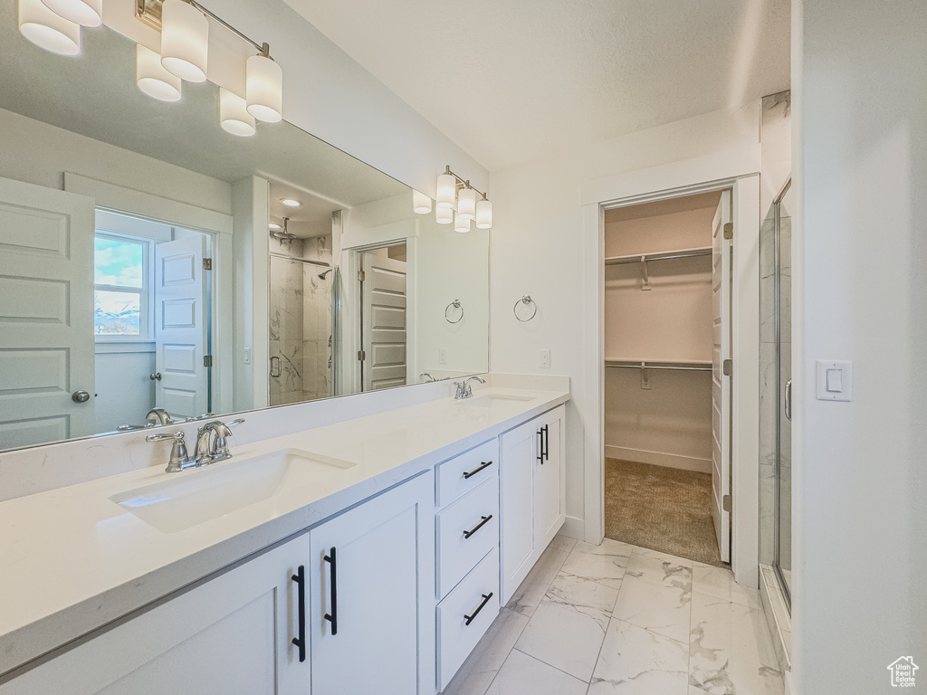 Bathroom featuring tile floors, walk in shower, dual sinks, and large vanity