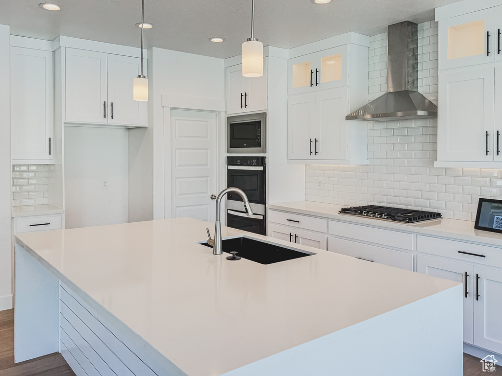Kitchen with tasteful backsplash, dark hardwood / wood-style flooring, stainless steel appliances, and wall chimney range hood