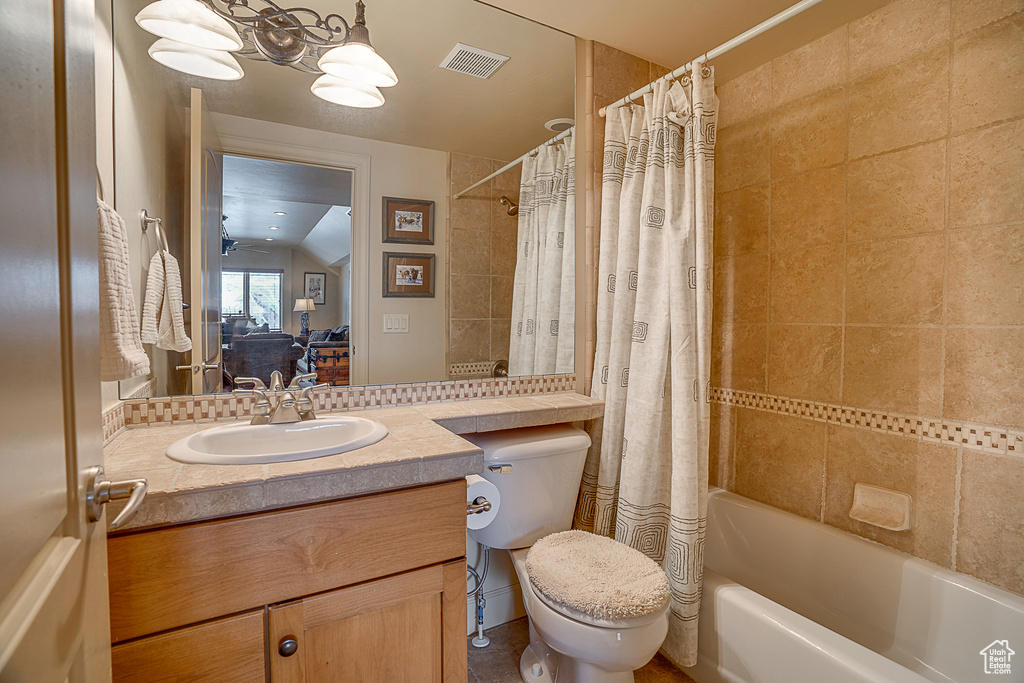 Full bathroom with shower / tub combo with curtain, vanity, toilet, lofted ceiling, and ceiling fan
