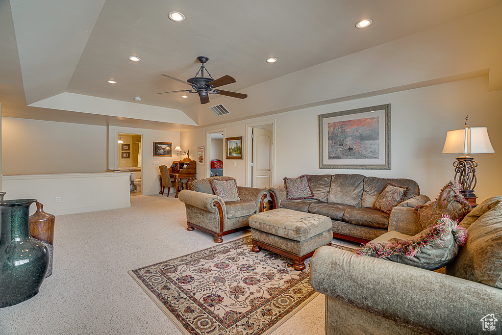 Living room with light carpet, ceiling fan, and a raised ceiling