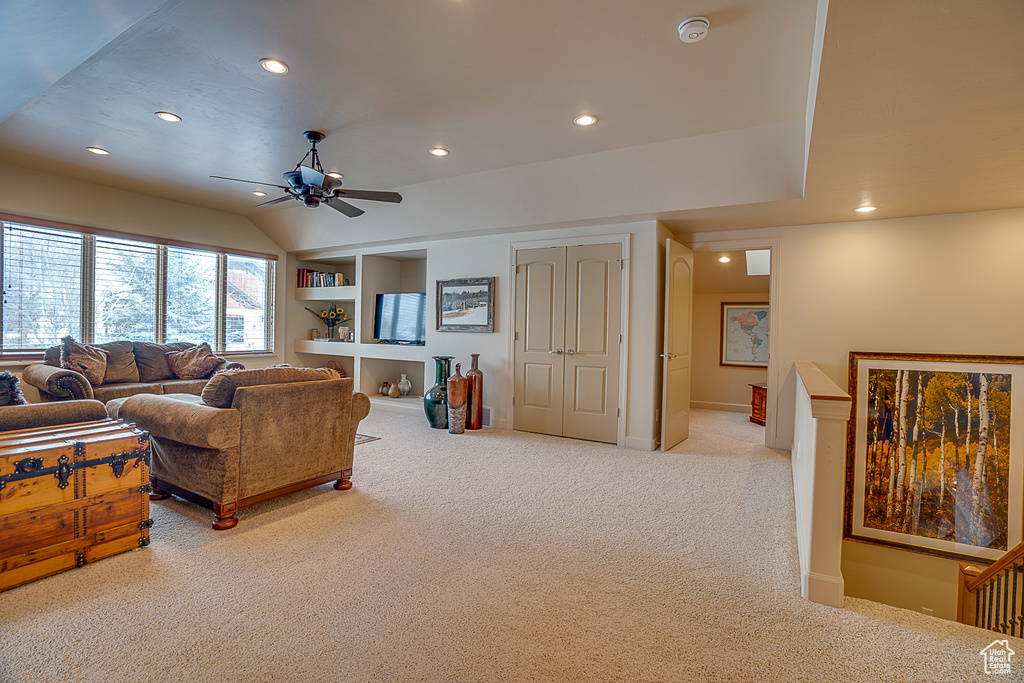 Living room featuring built in shelves, ceiling fan, and light colored carpet
